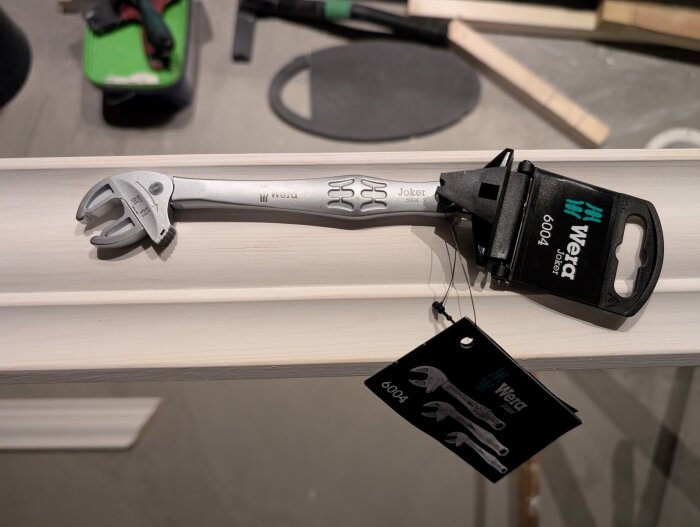 En skiftnyckel av märket Wera Joker 6004 ligger på en träyta. Verktygets förpackning syns bredvid.