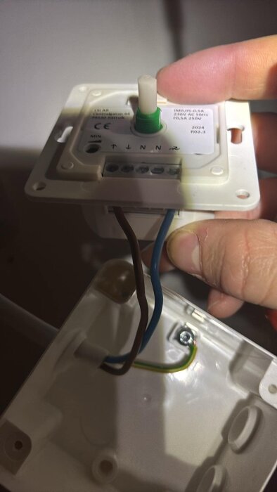 Ställbar dimmer med ledningar visad i närbild, hålls av en hand.