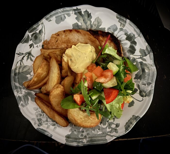 Tunna fläskkotletter med klyftpotatis, sallad med mango och chipotledressing på en tallrik.