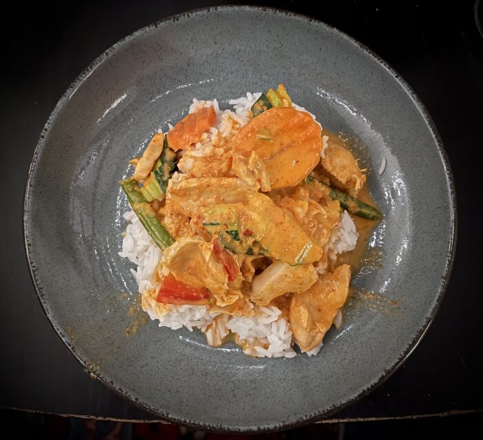 Tallrik med Gaeng Panäng, en thailändsk röd curryrätt med grönsaker och kyckling, serverad på ris.