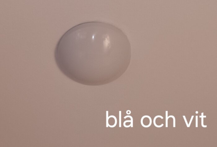 Rund taklampa i köket. Text "blå och vit" syftar på kabelfärger vid lampans uttag.