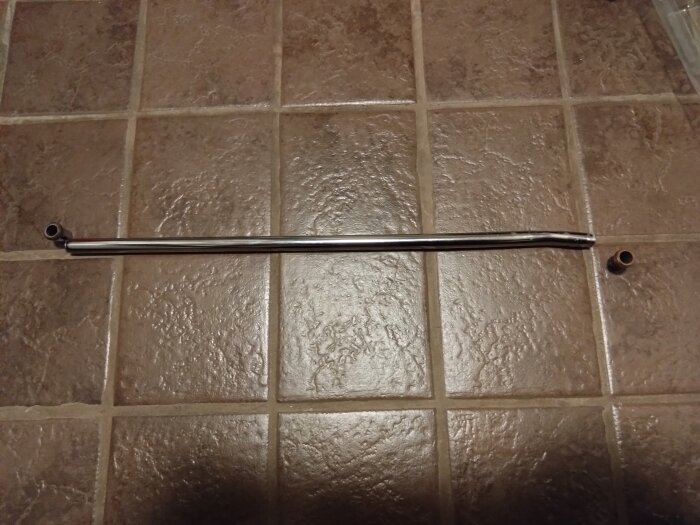 Ett avbrutet metallrör ligger på ett klinkergolv, med avbrott vid konorna i båda ändar, eventuellt skadat av galvaniska strömmar.