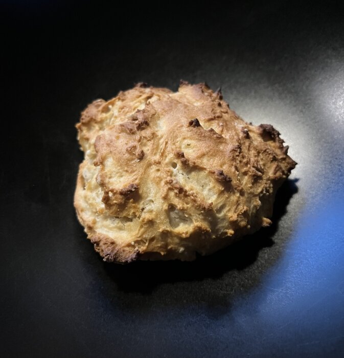 Hemgjord scone utan smör med olja och rågsikt, placerad på en mörk tallrik.