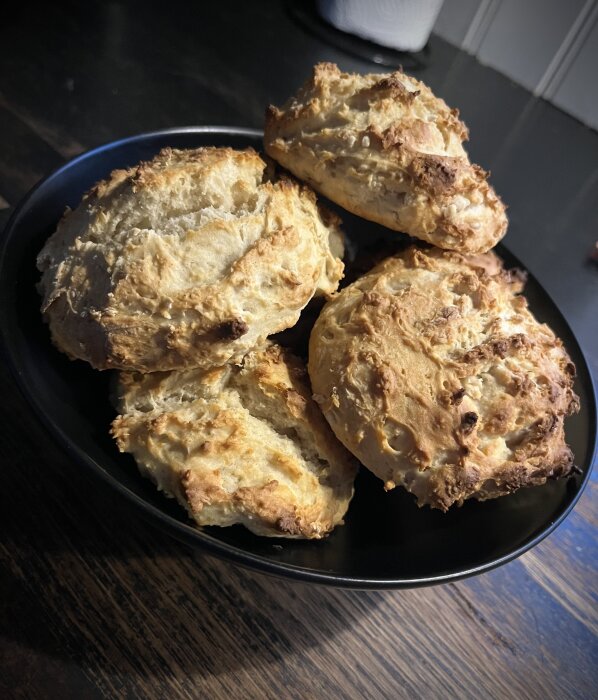Hemgjorda scones med rågsikt istället för vetemjöl, bakade utan smör, serverade på en svart tallrik på ett bord.