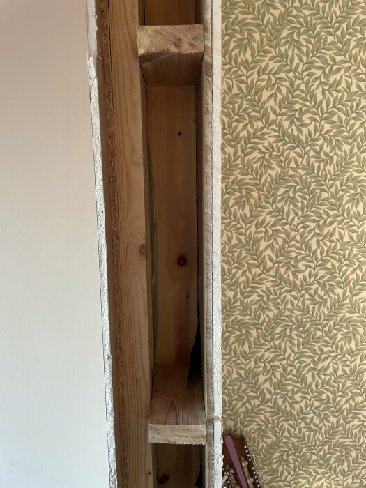 Inbyggd sektion med synliga träreglar och ångbroms i hushörn, med tapet och gitarr i bakgrunden.