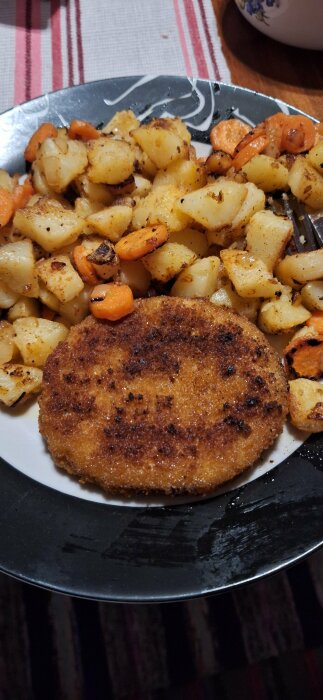 Köpekycklingschnitzel serverad med stekt potatis, morot och lök på en tallrik.