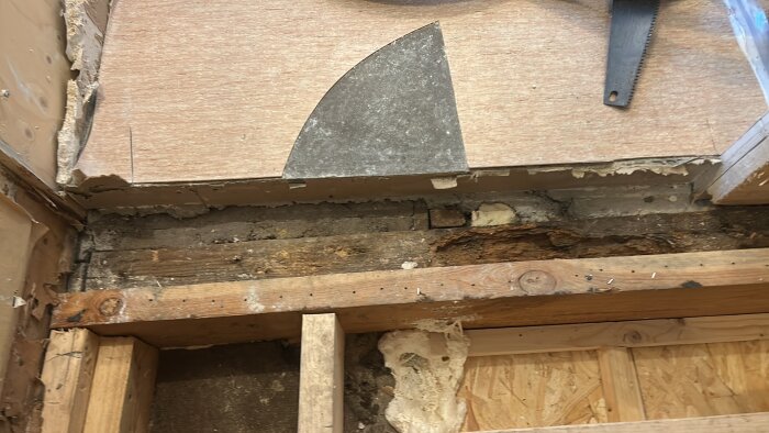 Golvet i ett badrum under renovering med en kombination av gjutet och reglat golv, visar olika material och strukturer i övergången.
