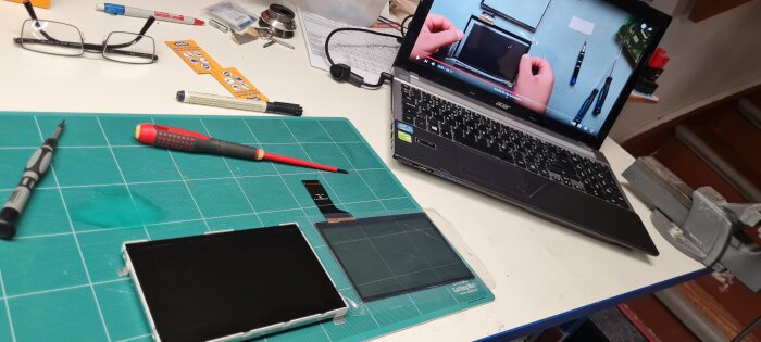 Laptop med instruktionsvideo för byte av bilnavigator, skärm och verktyg på arbetsbänk.