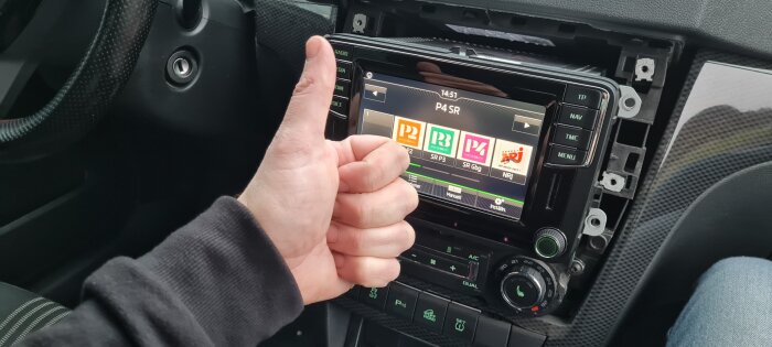 Tumme upp framför bilens navigationssystem med uppgraderad touch-panel.