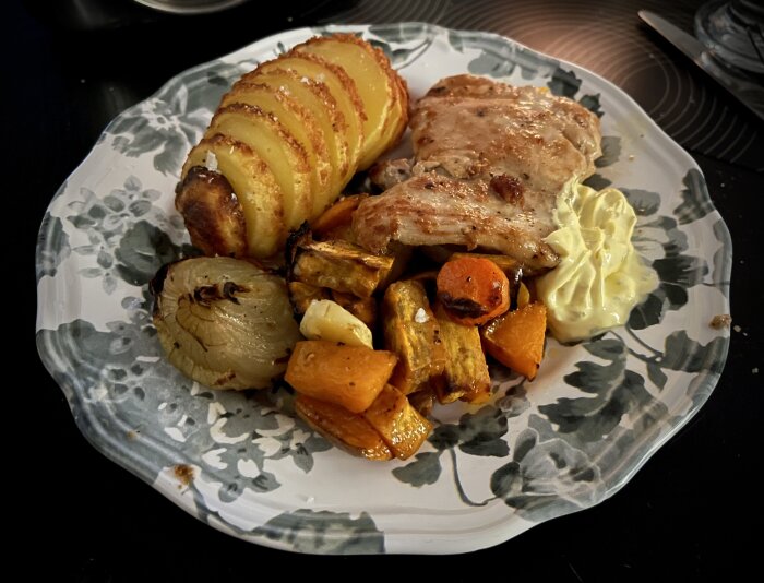 Stekt kycklinglårfilé med ugnsgrönsaker, hasselbackspotatis och sås på en tallrik.