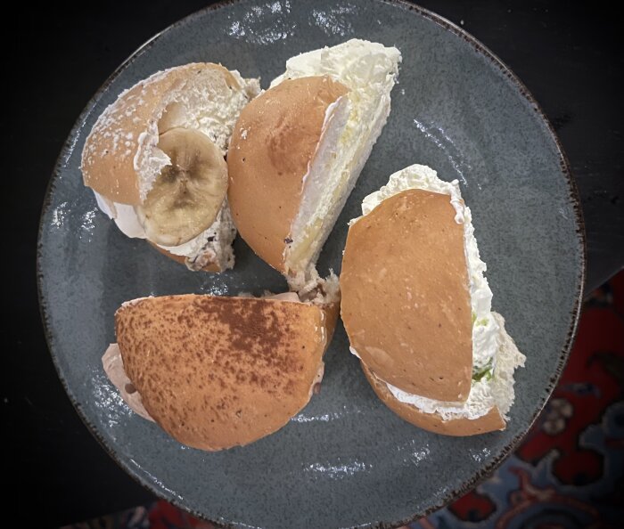 Fyra halverade specialsemlor med olika fyllningar ligger på en blå tallrik.