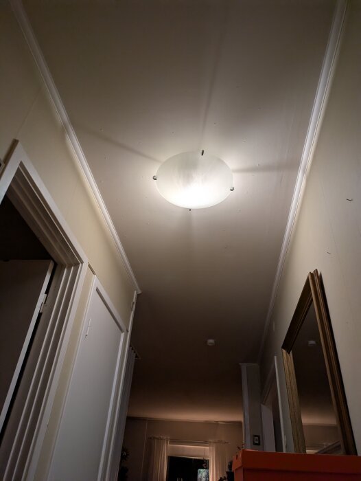 Tak i hall med ljusarmatur, där färg eller spackel släpper runt spikhuvuden, vilket ger behov av spackling, slipning och målning.