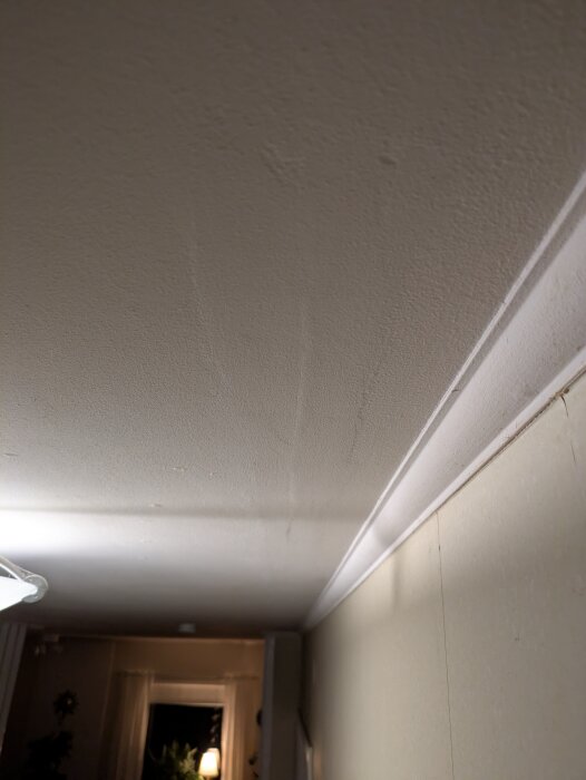 Tak med synliga spikhål och lös färg i hall, eventuellt behov av spackling och målning.