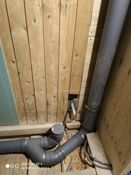 Ventilation pipe installation in a bathroom with standing pipes against a wooden wall, showing connections and fittings, querying compliance with Säker Vattens rules.