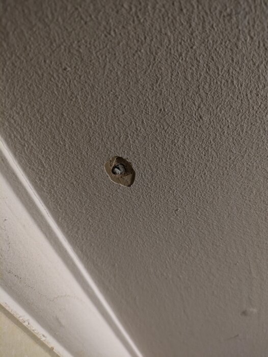 Närbild av en takyta med synligt spikhål som behöver spacklas innan målning efter att gammal färg skrapats bort.