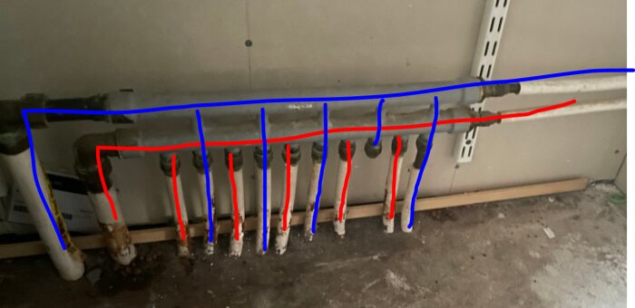 Röruppställning med färgmarkeringar i blått och rött visar varm- och kallvattenkopplingar i en väggmonterad installation.
