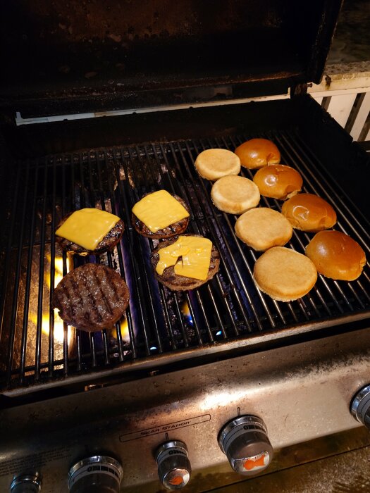 Hamburgare med ost och hamburgerbröd grillas på en utomhusgrill.