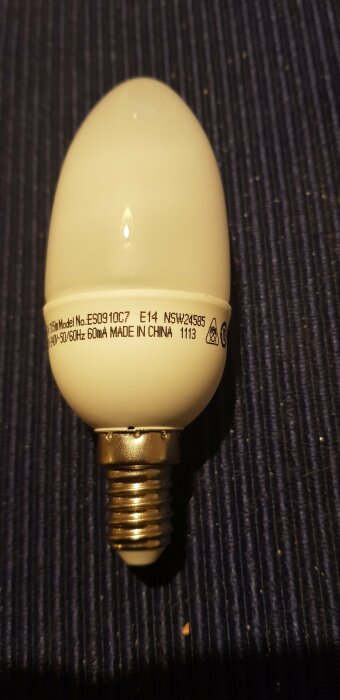 Närbild på en vit lysrörslampa med skruvsockel E14 och texten "Model No. ES0910C7, Made in China, 240V~50/60Hz, 60mA".