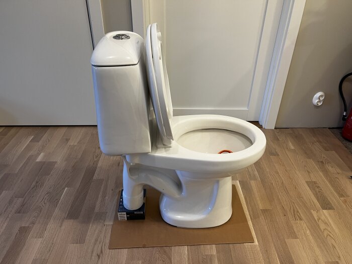 Wostman Ecoflush toalett med cistern och sits på trägolv.