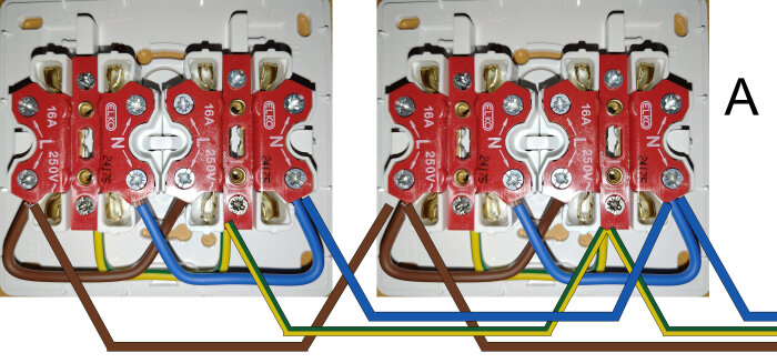 Närbild på parallellkopplade eluttag med röda plattor, märkta "ELKO 16A 250V", kopplade med bruna, blå och gröna/gula ledningar.