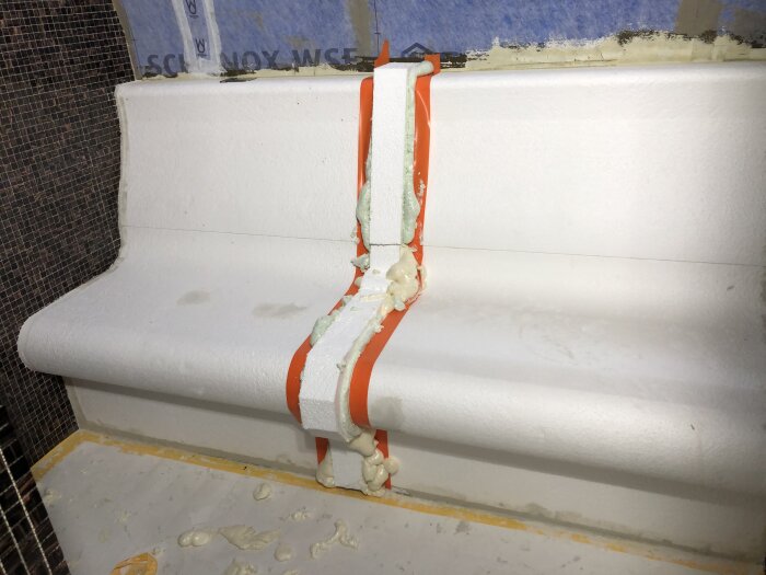 Vitt byggprojekt med orangel rör och fogmassa, del av renovering 2019.