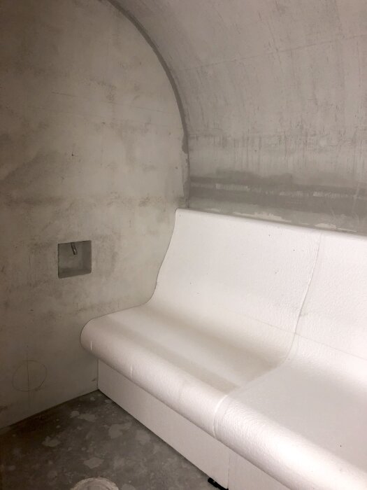 Vit sittbänk i betongrum, del av ett byggprojekt från 2019.