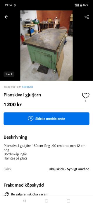 Verkstad med gjutjärnsplanskiva på grön arbetsbänk, omgiven av verktyg och hyllor i bakgrunden.