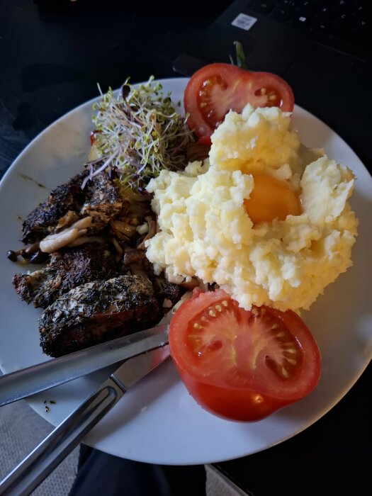 Tallrik med vitlök, chili och timjanmarinerade kycklingbröst, potatismos med rå äggula, egengroddade groddar och tomatskivor.