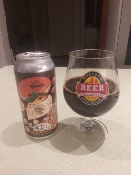 Burk av Basqeland Sobremesa öl och ett glas med mörk imperial stout på ett bord.