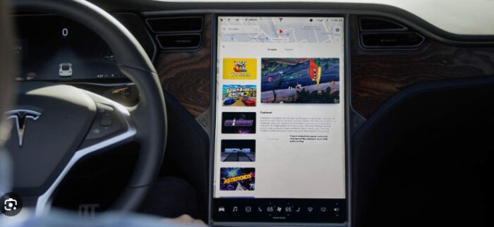 Bild av en Tesla-bilens interiör med central pekskärm, visar spel och kartfunktioner på skärmen.