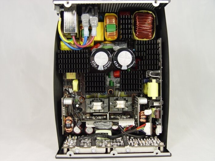 Inuti ett 1200W nätaggregat med synliga spolar, kondensatorer och kretskortskomponenter.