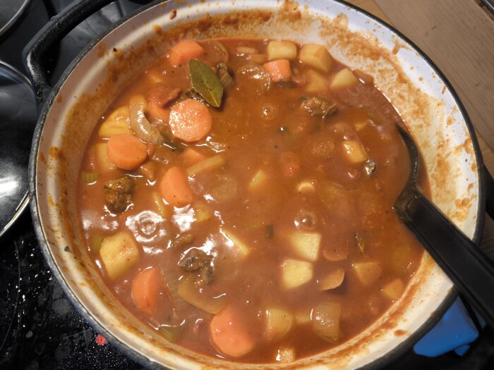 Ungersk gulasch puttrar i en gryta med morötter, potatis, lök och köttbitar, redo att serveras.