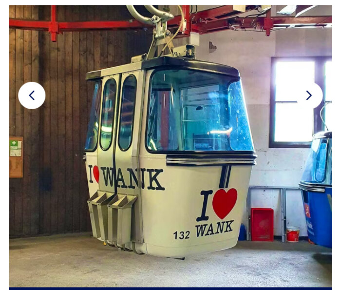 Kabinbana med texten "I ♥ WANK" inomhus, vitt och blått, redo för passagerare att färdas uppför bergen.