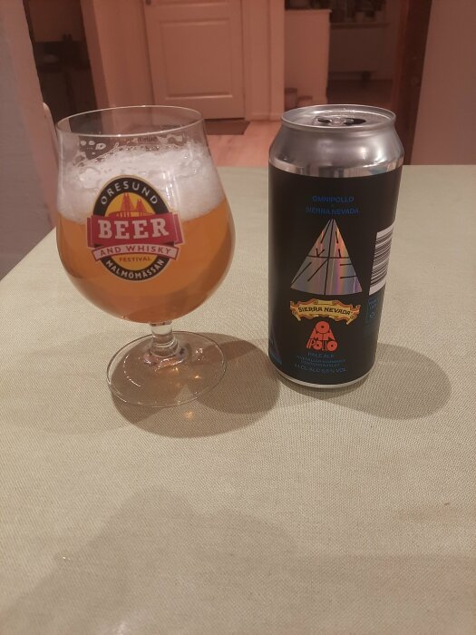 Ölglas med "Öresund Beer and Whisky Festival"-logga bredvid en burk Omnipollo Sierra Nevada på bord.