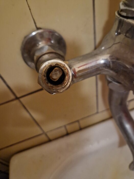 Närbild på en metallkran med avskruvat handtag, exponerad pigg och en mutterformad del som orsakar vattenläckage.