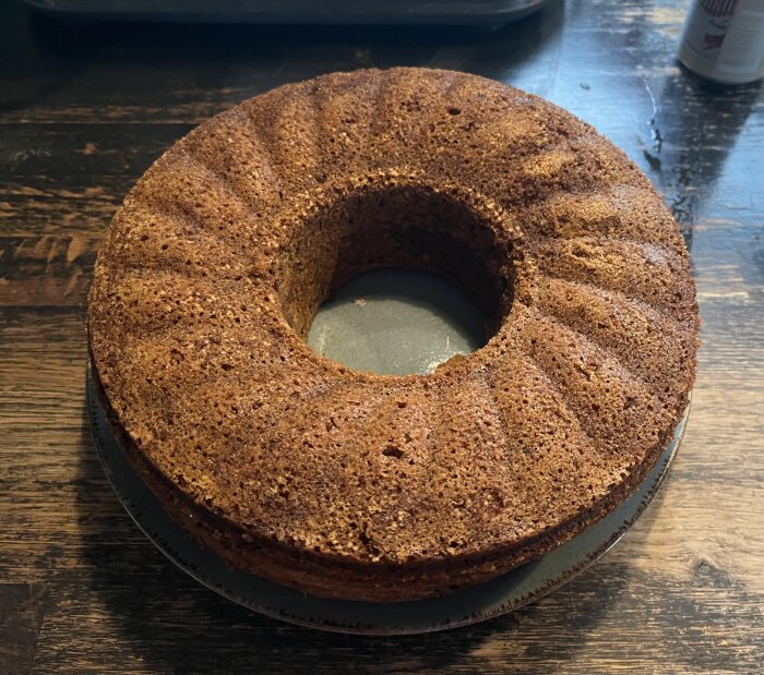 Rund, gyllenbrun banankaka med kardemumma på ett bord.