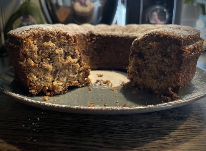 Banankaka med två skivor urtagna, serverad på ett fat, beströdd med florsocker.