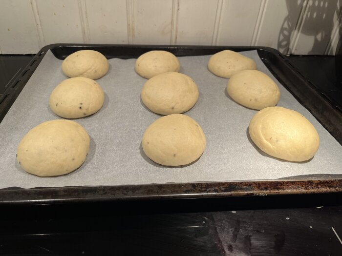 Ogräddade semmelbullar på en bakplåt, färdiga för ugnen.