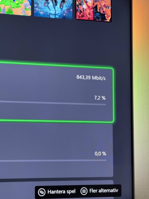 Nedladdningshastighet på 843,39 Mbit/s visas på en skärm, med ikoner för olika spel överst.