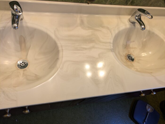 Två intilliggande handfat i ett badrum med märken och avlagringar, behöver renoveras.