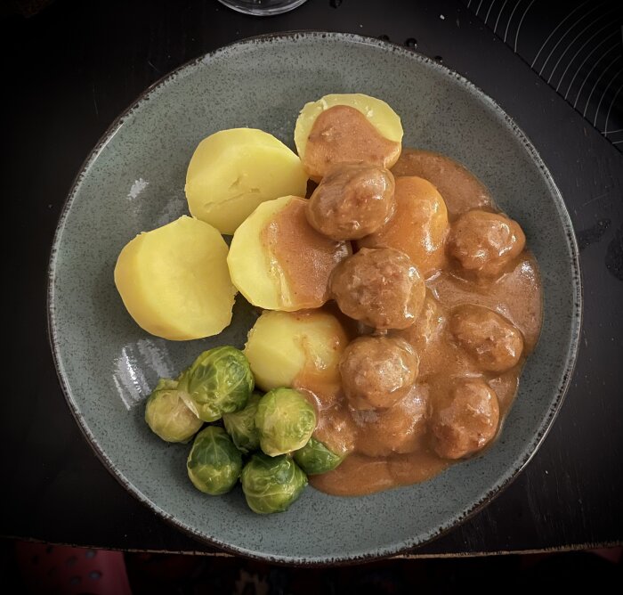 Tallrik med köttbullar i sås, brysselkål och kokt potatis.