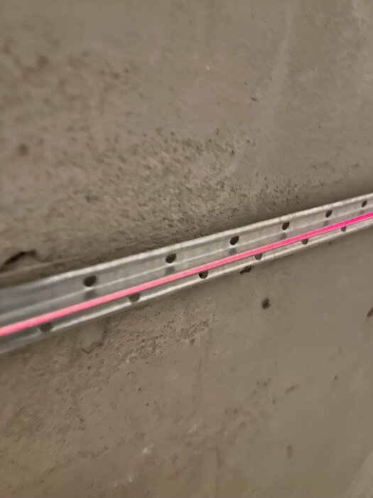 Laserlinje över fixerad avdragsbana på spacklad lättbetongvägg, visar inpassning för avjämning.