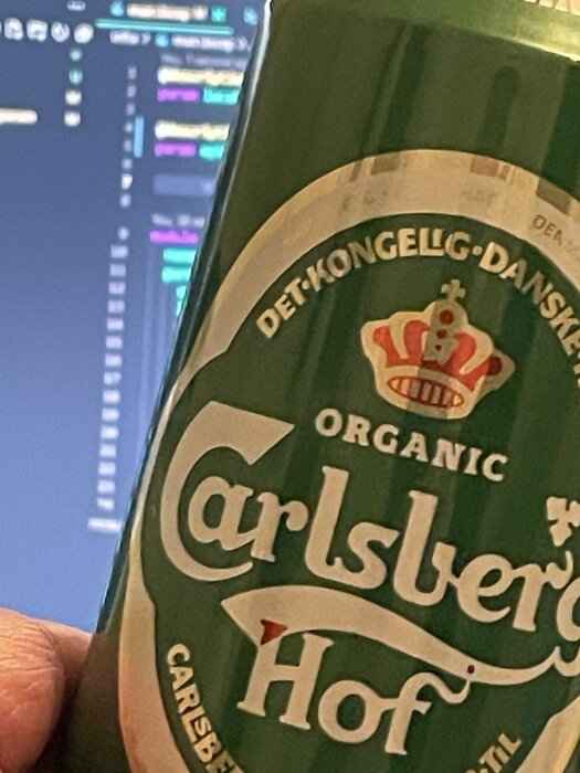 Bärsflaska med Carlsberg Hof, bakgrund av datorskärm med kod.
