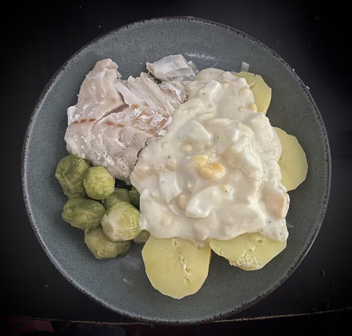 Tallrik med kokt torsk, potatis, brysselkål och äggsås.