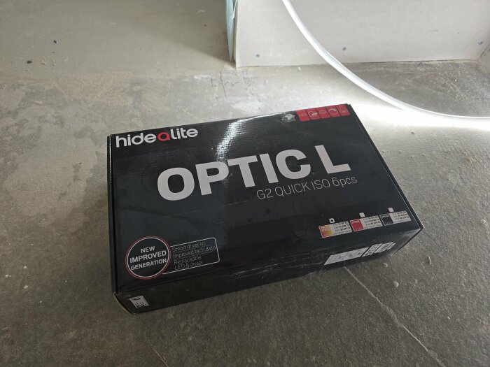 Förpackning med Hide-a-lite Optic L G2 Quick ISO LED-lampor på ett bänkskiva, används för belysningsinstallation med Zigbee-dimmer.