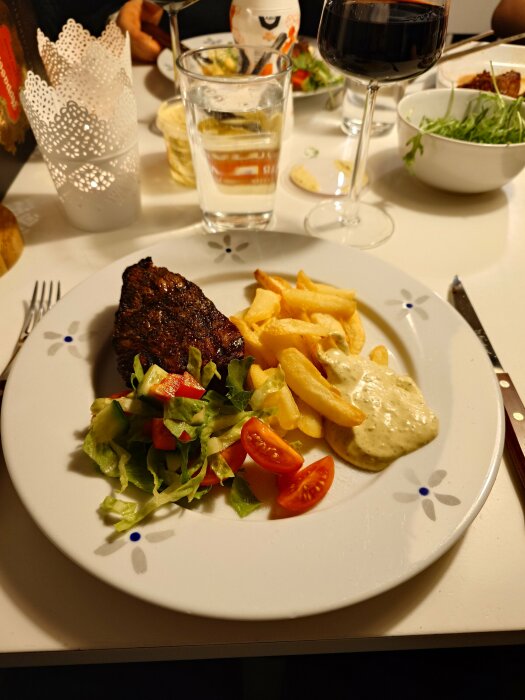 Grillad rostas med pommes frites och bearnaisesås, serverad med sallad och tomater på en tallrik.