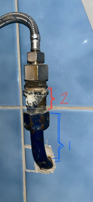 Två kopplingar på ett rör i ett badrum, märkta 1 och 2. Koppling 2 ska eventuellt tas bort. Blått kakel syns i bakgrunden.