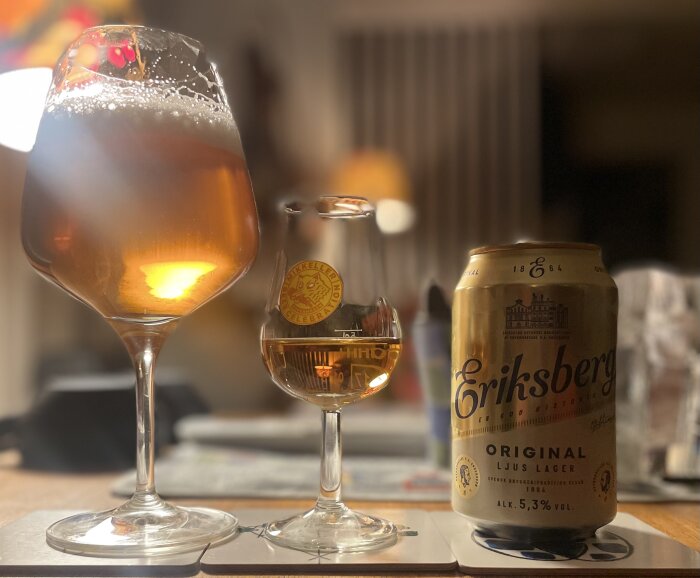 Två ölglas, ett med öl och ett med rom, samt en burk Eriksberg original ljus lager står på ett bord.