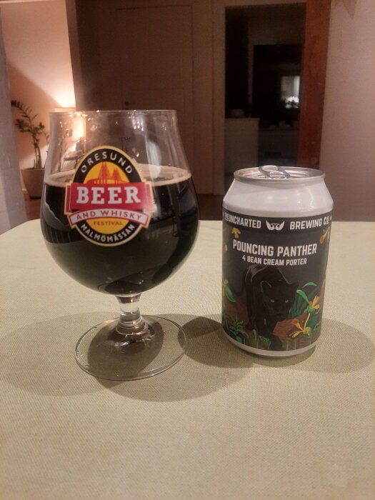 Glas och burk med Pouncing Panther 4 Bean Cream Porter öl på ett bord.