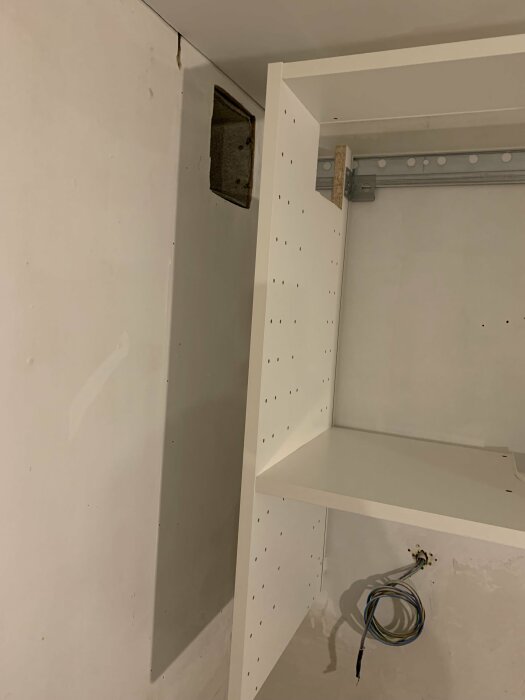 Vägg med rektangulär öppning för ventil och del av köksrenovering.